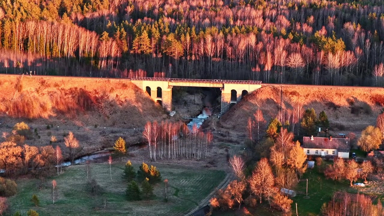 Ilmakuva rautatiesillasta ja virtaavasta joesta kauniissa kultaisen tunnin auringonlaskussa