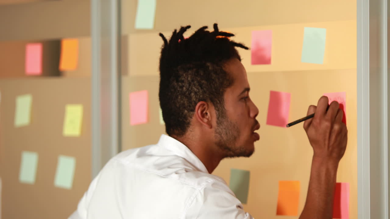 Smiling casual businessman writing on sticky notes