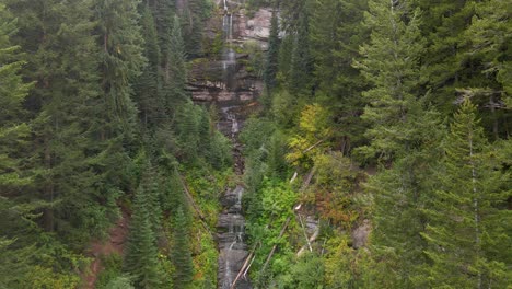 Aerial-view-of-the-water-of-a-waterfall-falling-down-the-rocks-in-the-middle-of-the-green-forest