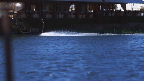 sportsman training wake boarding on water surface of modern water-skiing complex