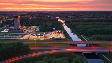 beautiful illumination of highways, parking lots and buildings at dusk time. lights of the city at backdrop. orange sky over the scenery. aerial perspective.