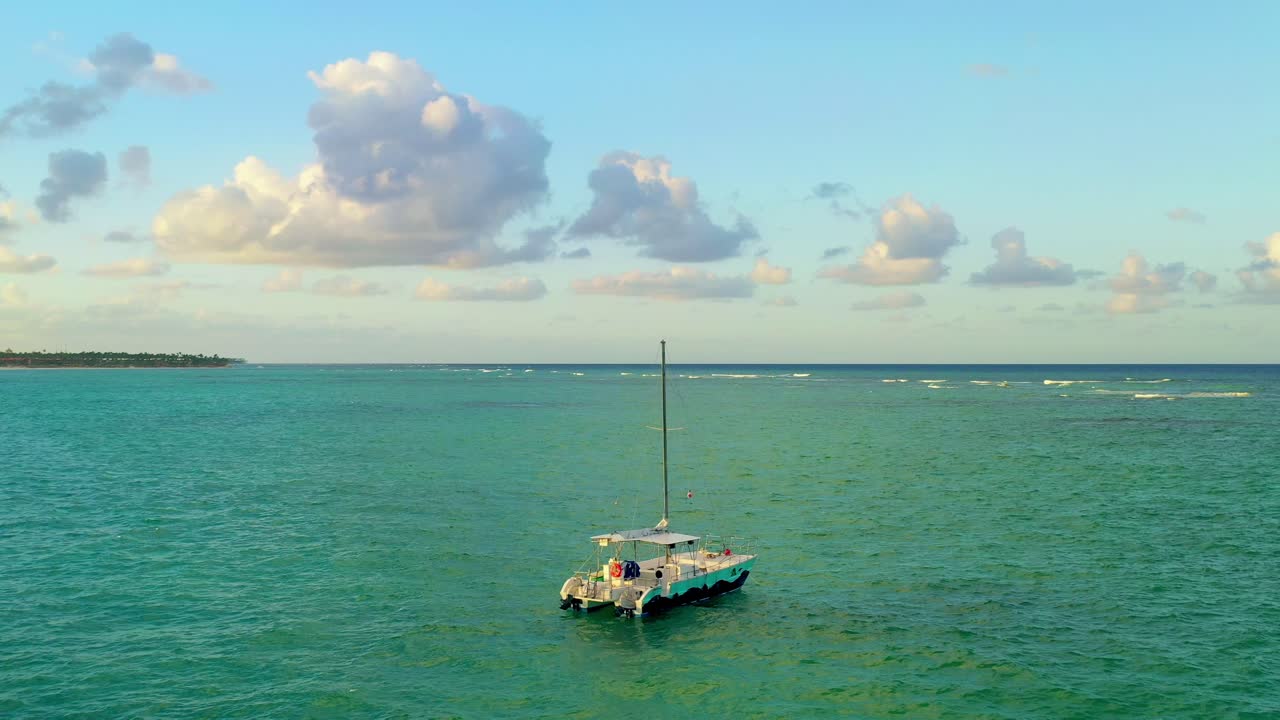 barco catamarán de sobrevuelo panorámico amarrado en aguas verdes del océano, enfoque aéreo superior