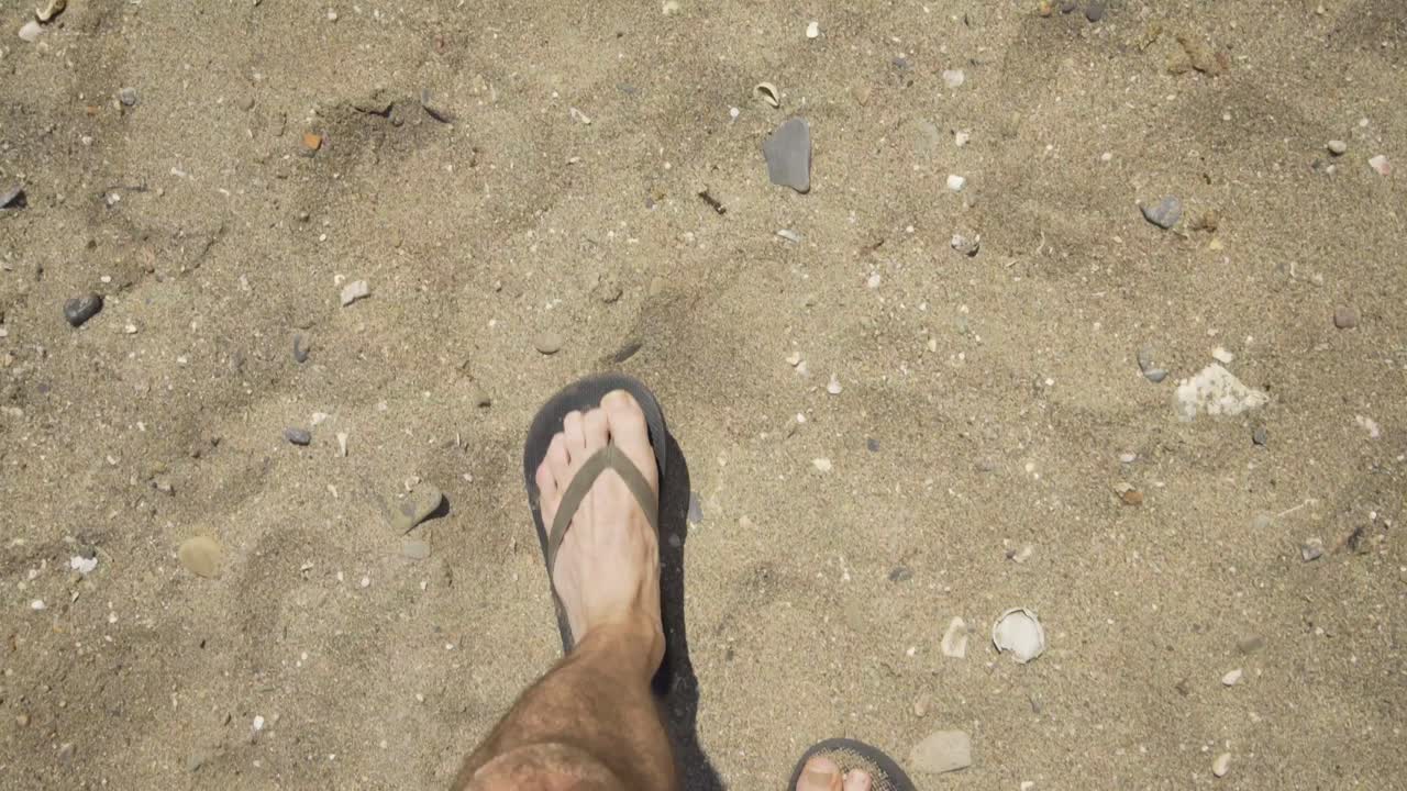 Male wearing Flip Flops walking in the dry sand on the Beach at Cala de Mijas on the Costa Del Sol in Southern Spain.