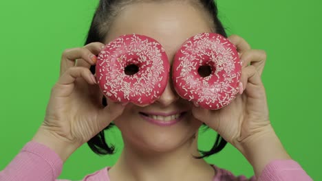 mujer con rosquillas sobre los ojos, sonriendo y riendo