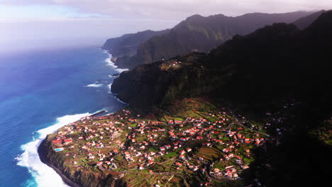 aerial flight over small village of ponta delgada with houses located on hilltop with beautiful coastline and blue ocean during sunlight