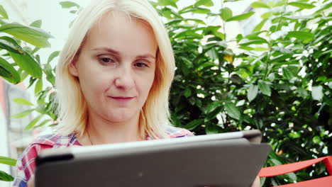 porträt einer jungen frau mit einem tablet in einem straßencafé