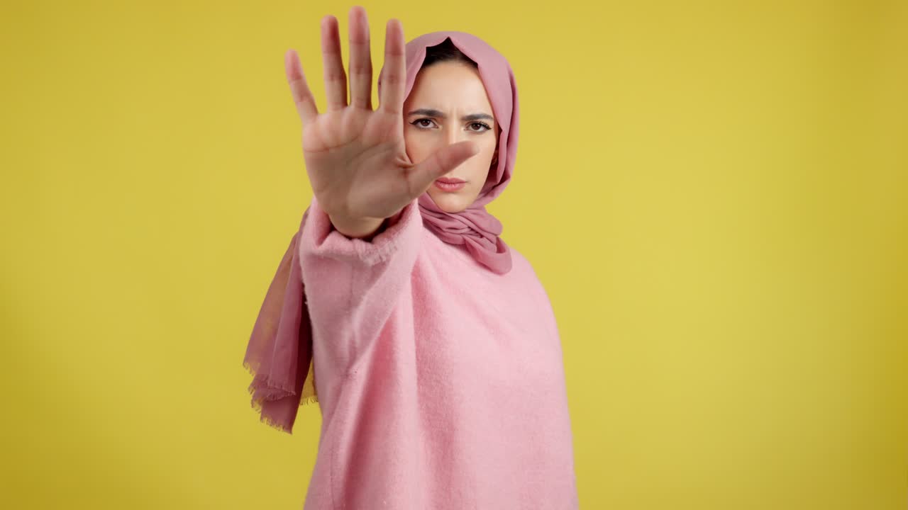 Donna con hijab che fa un gesto di stop con la mano.
