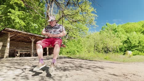 Senior-man-in-contemplative-mood-relaxes-on-swing-in-peaceful-woodland-location