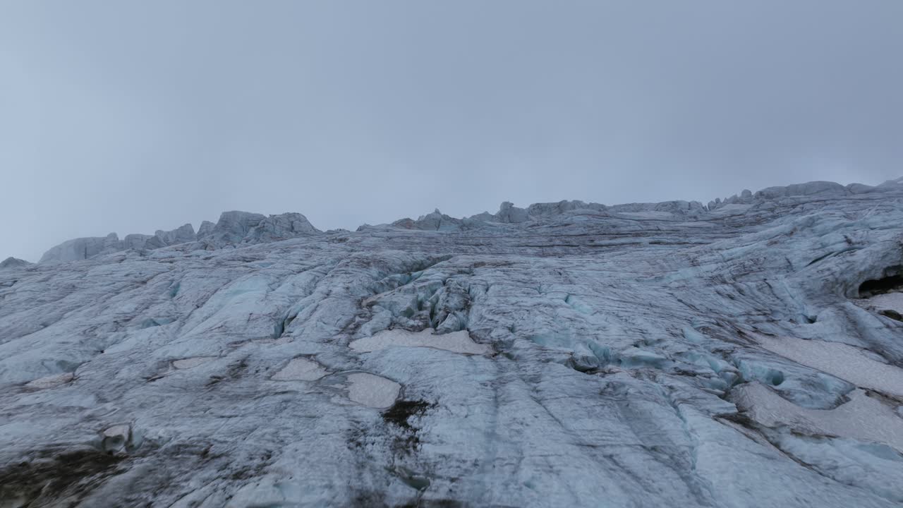 Close aerial flying over surface of Steingletscher glacier, showing textures of ice and snow on a cloudy day, Susten Pass, Swiss Alps, Switzerland