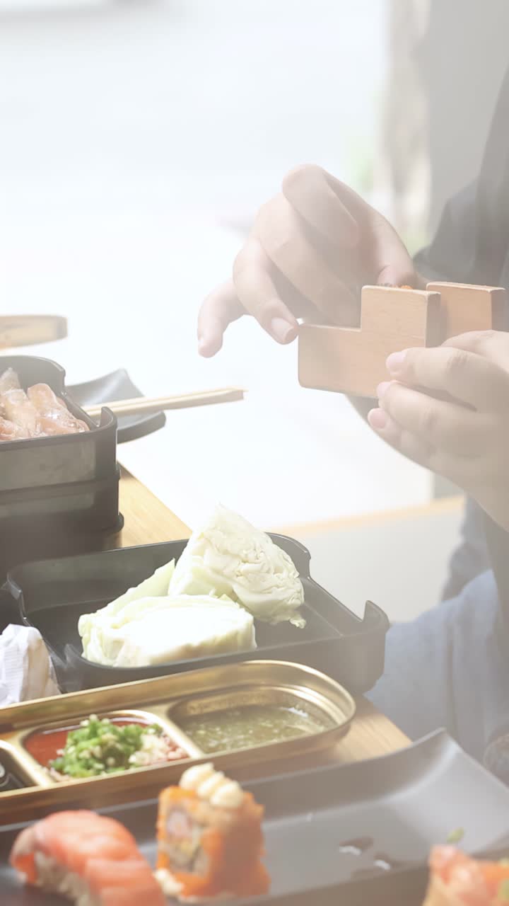 柔らかな自然光の下、食事客が盛り合わせの寿司の横に木製の箸置きを並べるクローズアップ