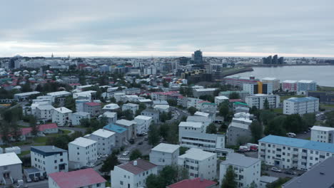 Drone-view-of-Reykjavik,-capital-and-largest-city-in-Iceland,-on-the-shore-of-Faxafloi-Bay.-Birds-eye-panoramic-view-of-Iceland-capital-city-with-colorful-rooftops-and-coastline.-Travel-destination