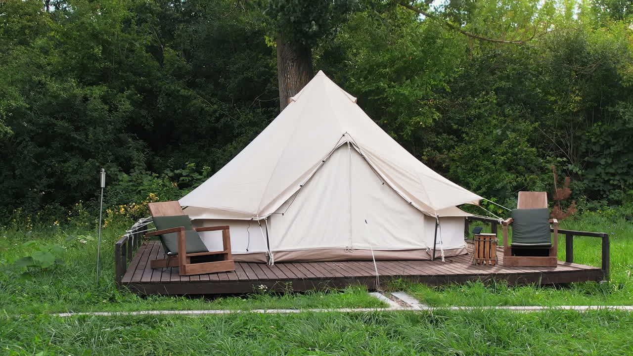 Teltta puisilla tuoleilla glamping-alueella, riippumatto, vehreä metsä ympärillä