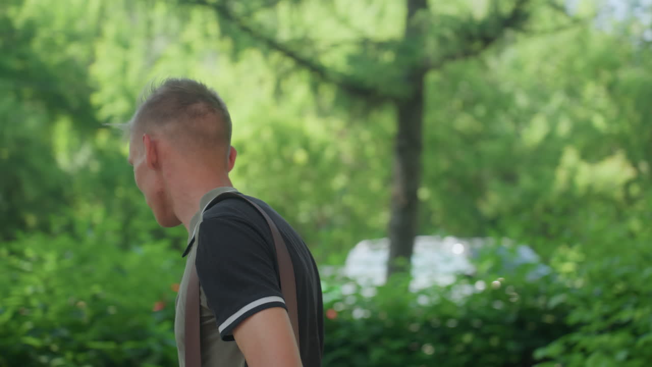 Youthful Man Glimpses Nature, Male Youth Observes Leafy Surroundings, Young Man Peers Through Tree Branches Carefully, Teenage Male Scans Greenery With Intense Concentration And Subdued Stance