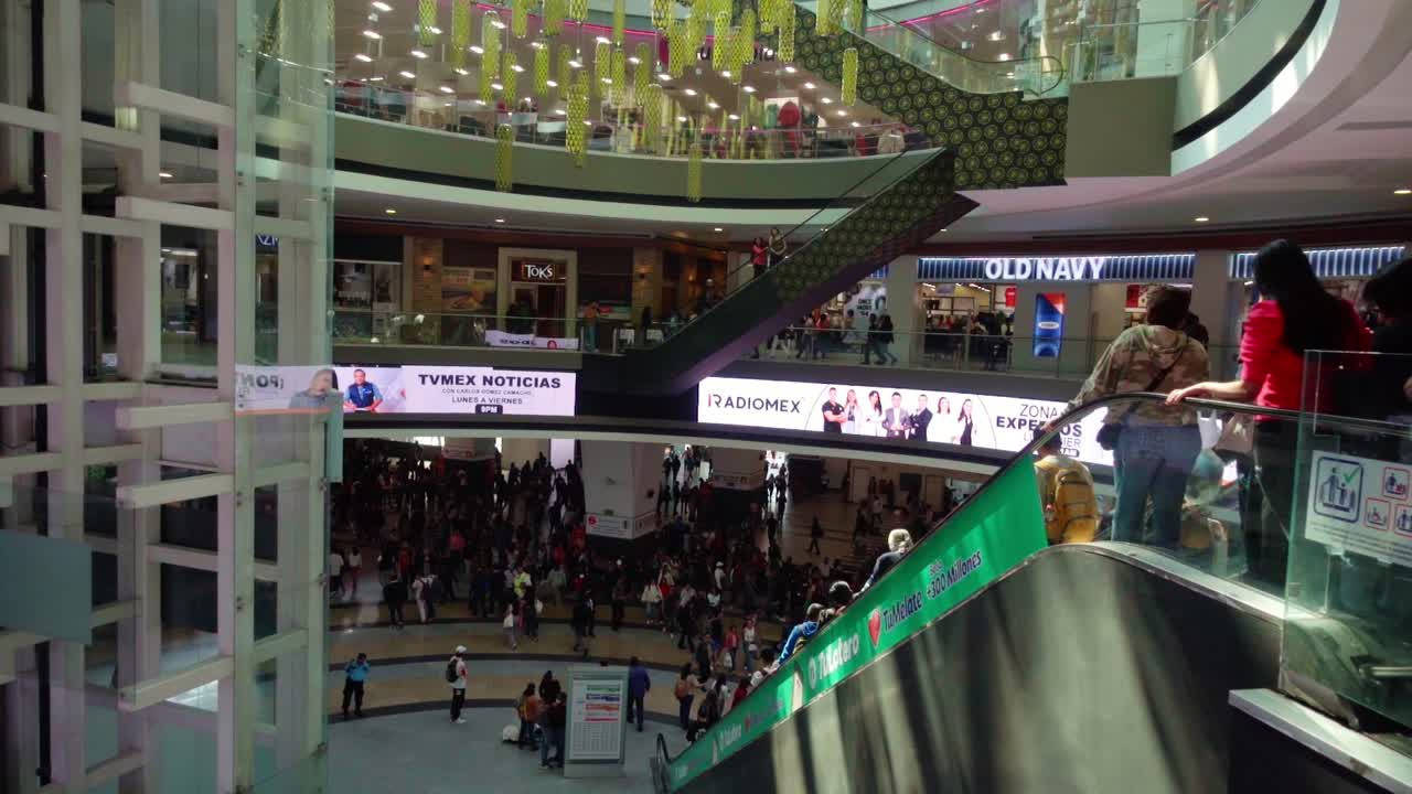 Busy shopping mall with crowds moving on multiple levels under bright lights in a bustling environment