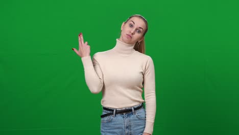 mujer desinteresada aburrida imitando un disparo de arma en el templo en pantalla verde. retrato de una joven caucásica gestando en el fondo de chromakey. aburrimiento y emociones