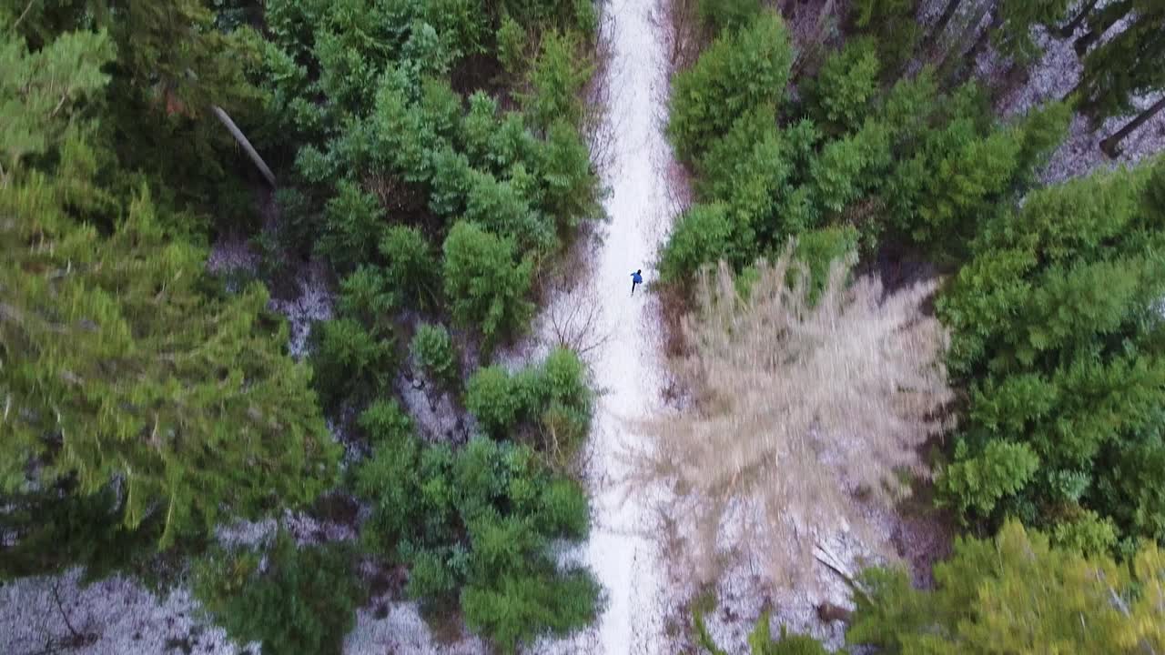 A young adult male runs in the winter through the woods training and doing their health