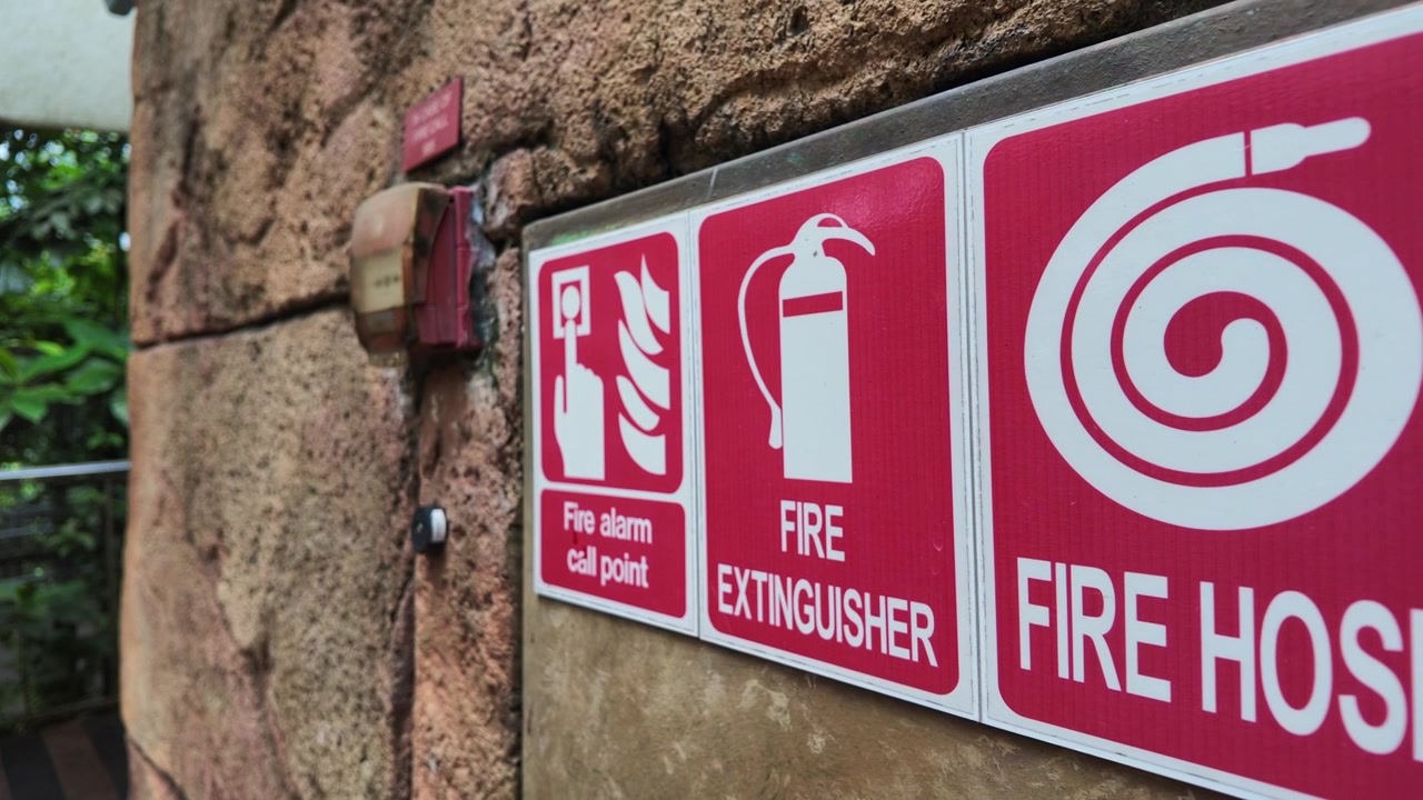Skilte med brandsikkerhedsudstyr på en tekstureret stenmur