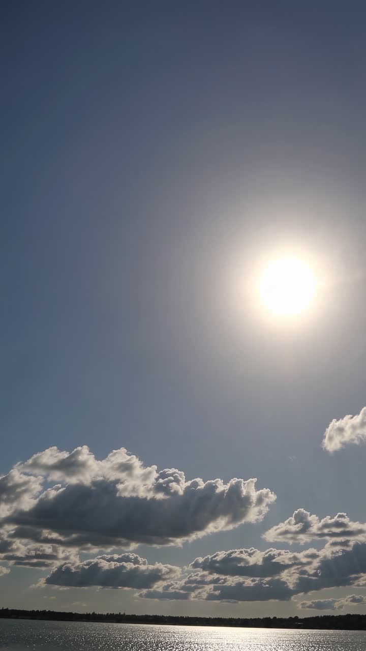 Un video sereno cattura una vista dal basso del sole che splende intensamente su un lago tranquillo