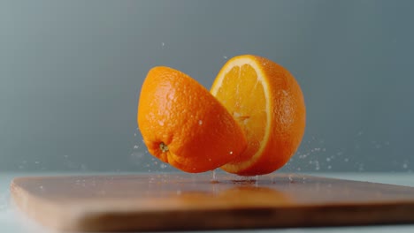 dos pedazos de naranja cayendo en una tabla de cortar