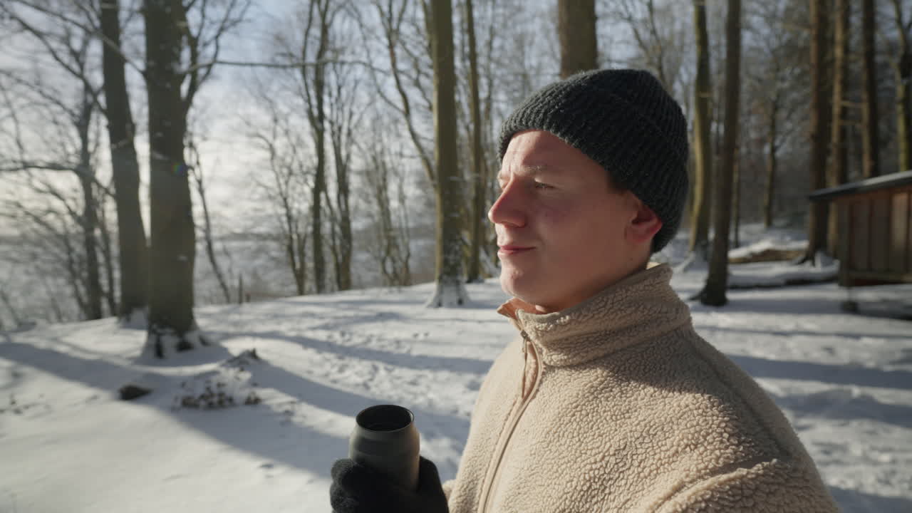 빛이 빛나는 겨울의 순간은 눈 인 숲에서 뜨거운 음료를 마시며 테르모스를 마시고 있는 사람입니다.