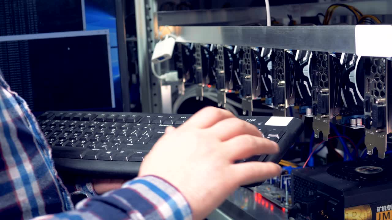 manos cercanas de un especialista en criptomonedas monitoreando el proceso de minería escribiendo código en un teclado.