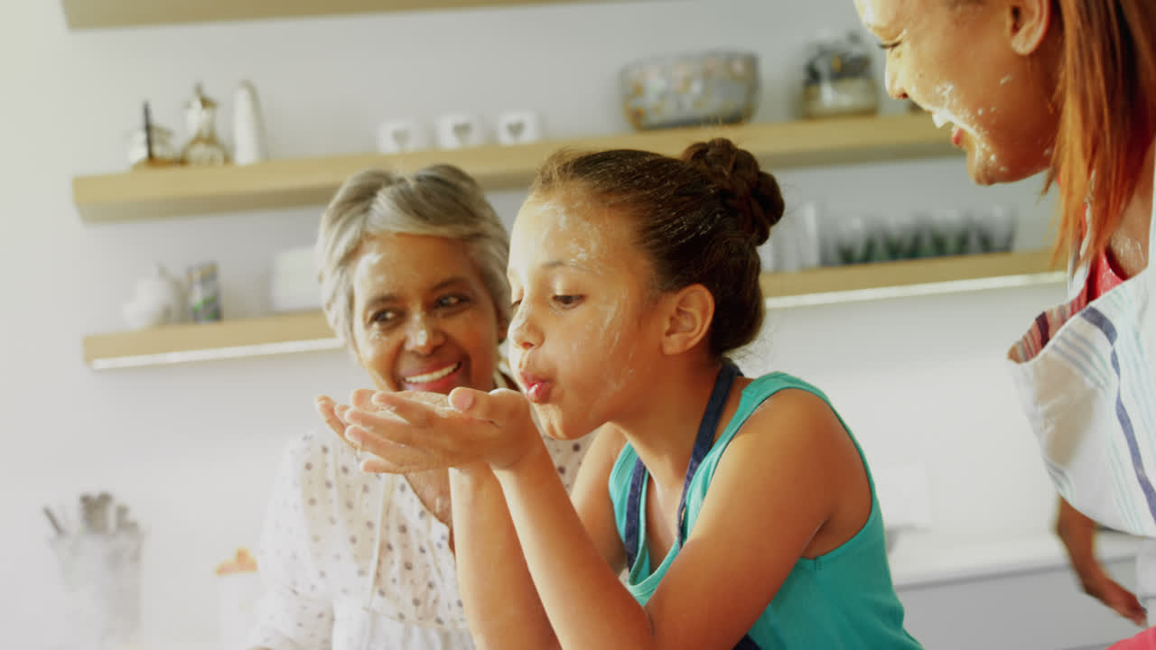 Happy multi-generation family blowing flour in kitchen 4k