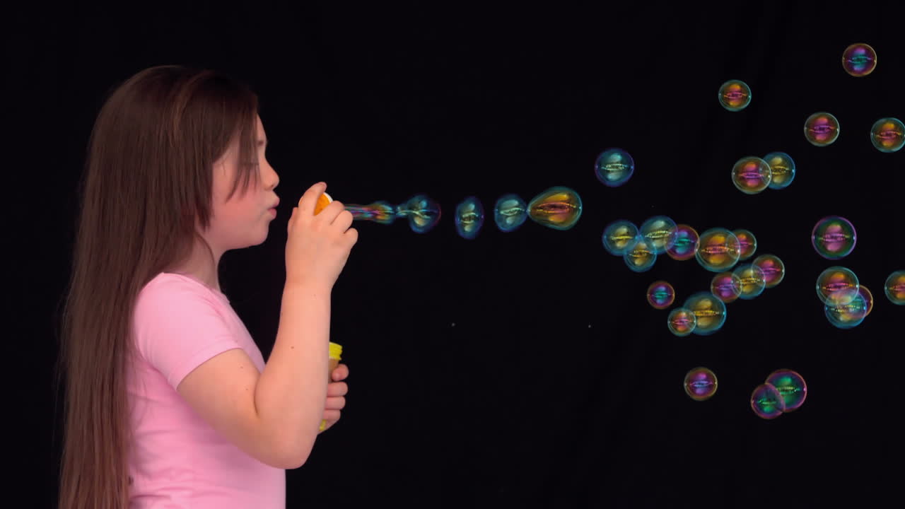 Side view of a little girl making bubbles