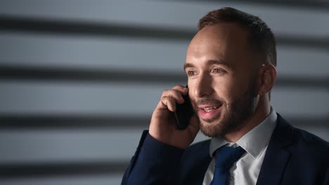 primer plano sonriente jefe masculino hablando teléfono inteligente discutiendo negocio noche oficina sombra de celos