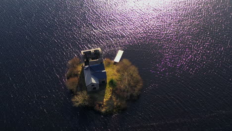 dynamic aerial pullback of o'flaherty castle, with sun rays reflecting on ballynahinch lake.