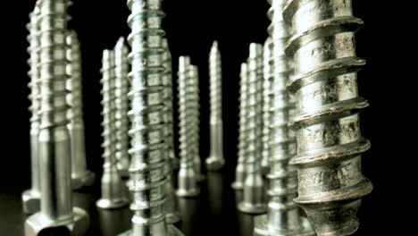 close-up of a group of metal screws standing upright on a dark background