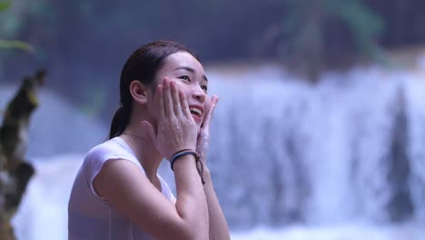woman washing face by waterfall