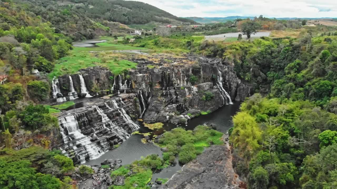 A breathtaking overhead shot of cascading waterfalls hidden within lush jungle terrain, where crystal-clear streams flow into vibrant pools beneath thick forest canopy.