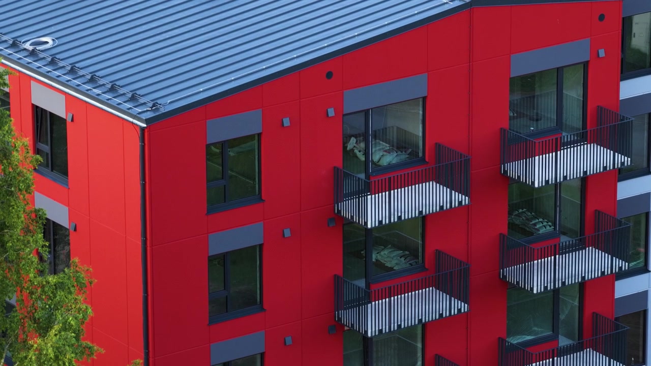 Çok sayıda balkon ve pencereye sahip modern bir konut binasının kırmızı cephesi