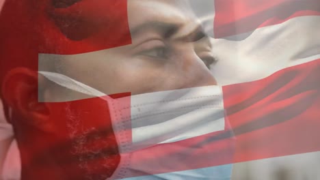 animation of flag of switzerland waving over african american man wearing face mask in city street