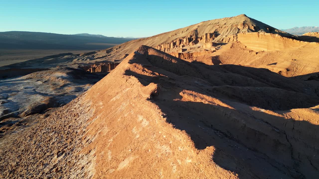 4K cinematic panorama of jagged ridges and white flats near San Pedro de Atacama bathed in evening sunlight
