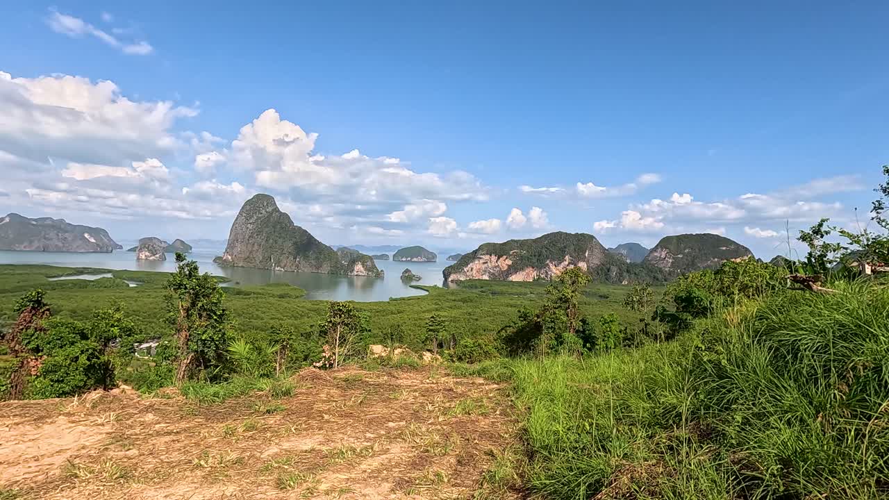 A serene landscape of Phang Nga Bay with lush greenery, limestone cliffs, and clear blue skies captured in daylight
