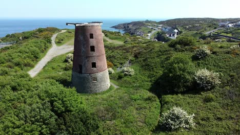 amlwch port red brick disused abandoned windmill aerial view north anglesey wales slow pull back reveal