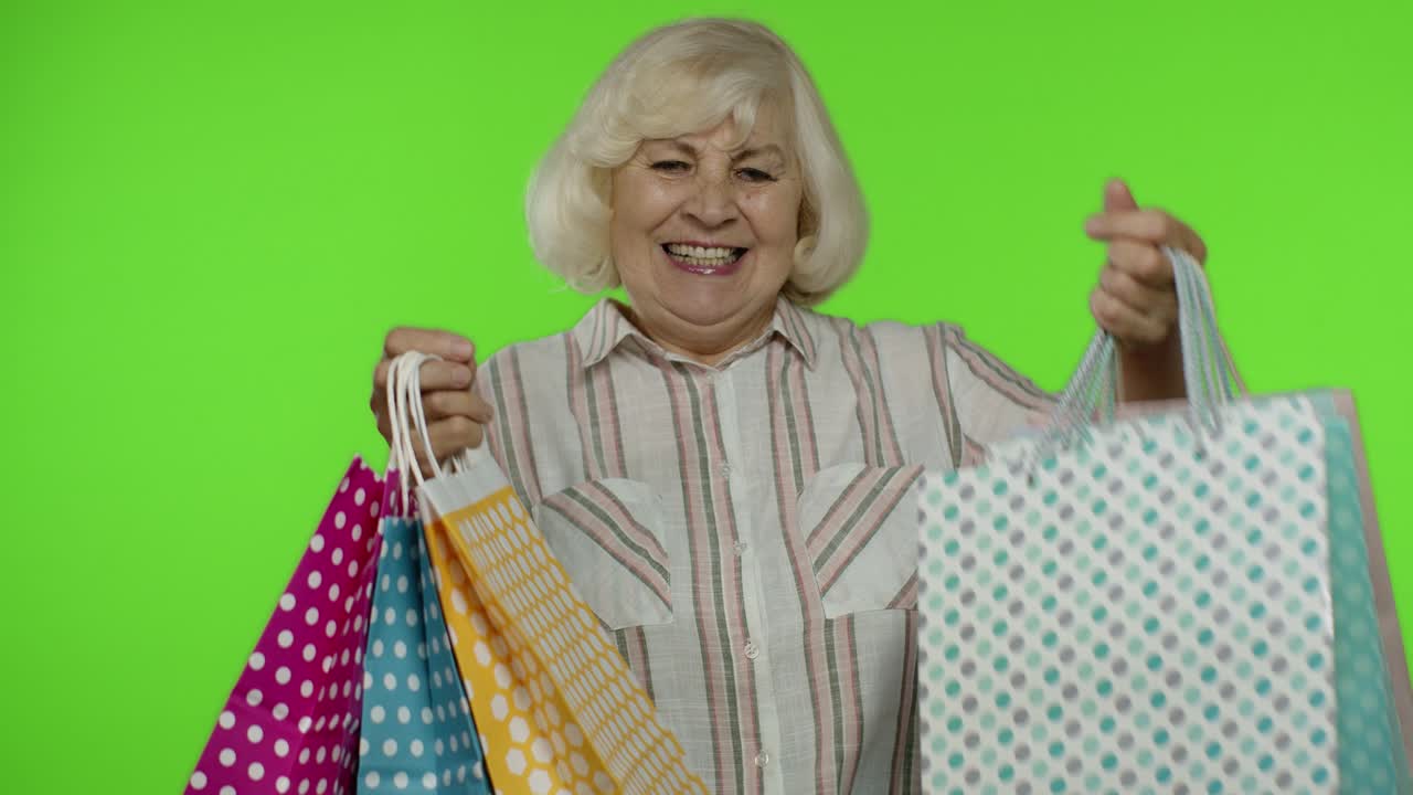 abuela mayor levantando bolsas de compras, celebrando, satisfecha con la compra, descuento. llave de croma