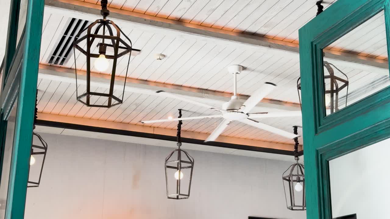ventilador de techo y linternas en un interior moderno con acentos azules, mostrando movimiento dinámico de la cámara y iluminación brillante