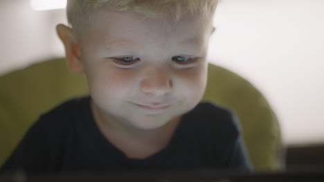 little boy looks at glowing screen resting in high chair