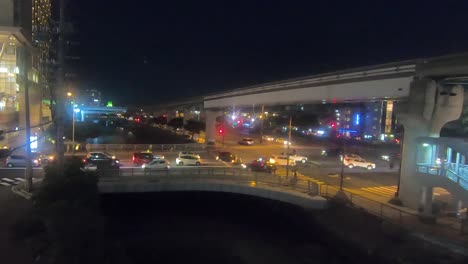 Timelapse. Naha City intersection at night. Trains travel along monorail line. Circa May 2019