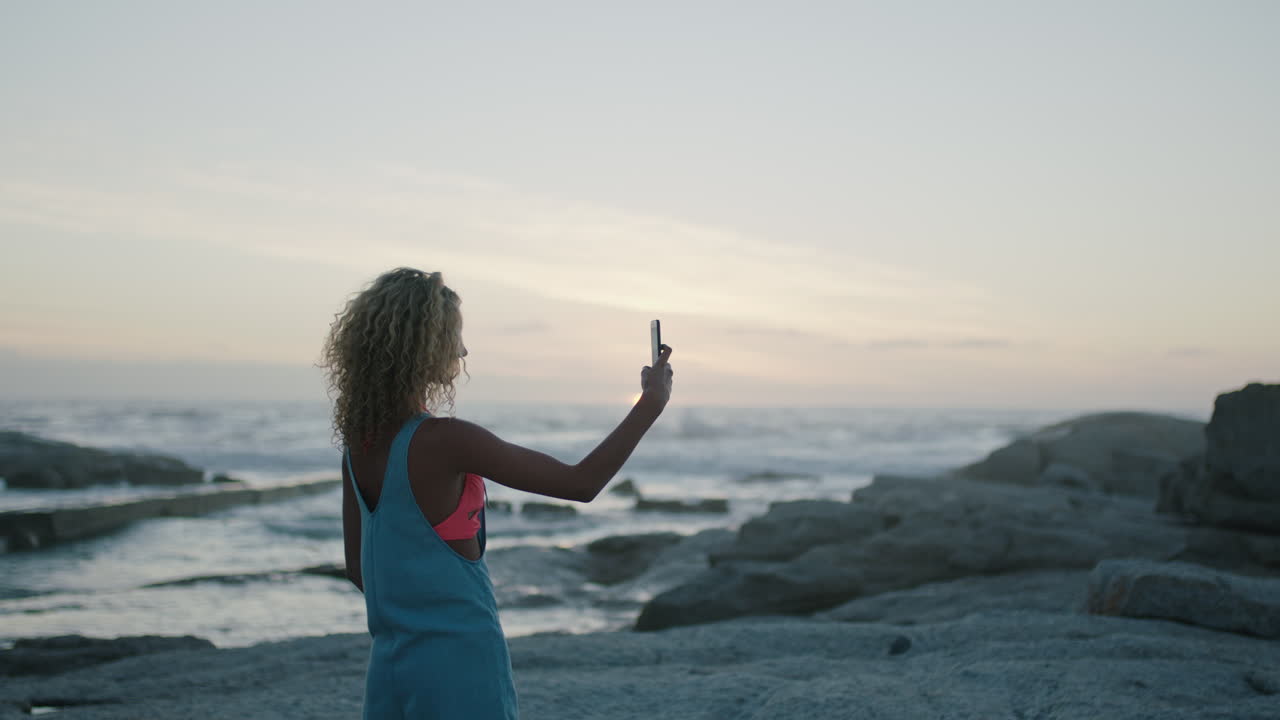 mujer joven tomando fotos en la playa al atardecer hermoso paisaje pacífico
