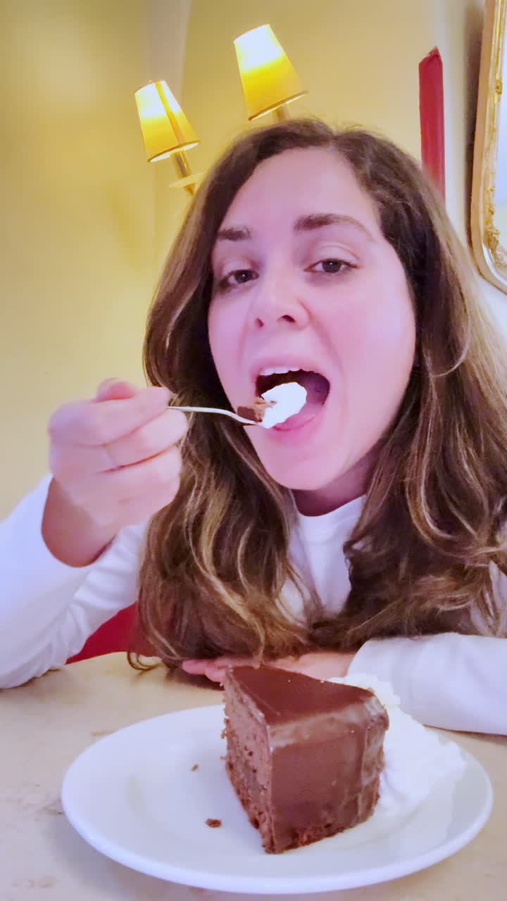 Mujer joven disfrutando de una porción de pastel de chocolate en una cafetería.