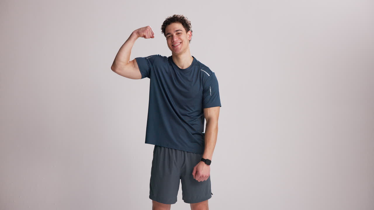 Young Man Flexing Bicep and Smiling in Studio