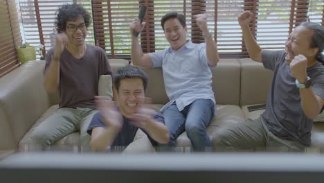 아시안 메이트 그룹이 집에서 tv에서 스포츠 대회를 보고 있습니다.