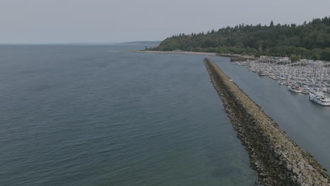 Slow-aerial-pan-to-the-right-over-a-rock-barrier-revealing-a-large-leisure-boatyard