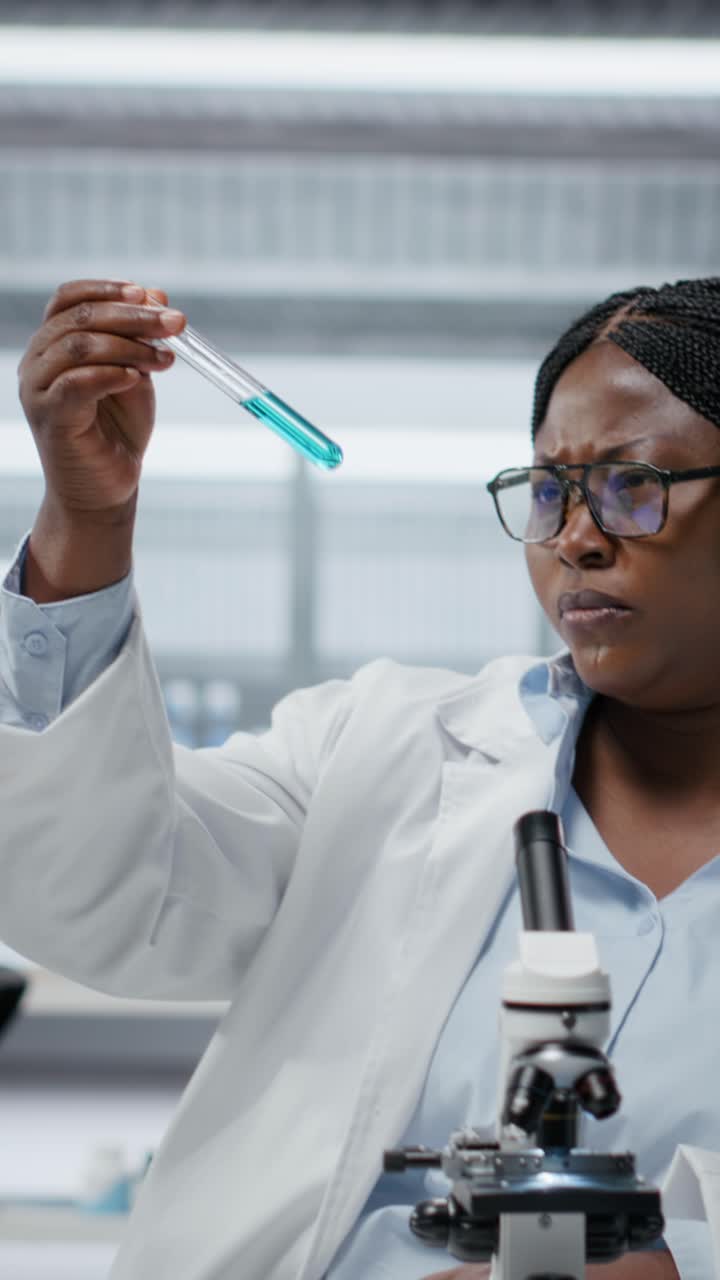 Vertical video Lab materials scientist investigates blue liquid polymer properties in test tube