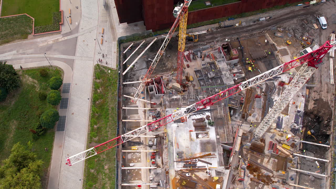 fotografía de arriba de grandes grúas industriales en un gran sitio de construcción con maquinaria y acero en un día soleado - ciudad de gdansk, polonia - vista de arriba de un avión no tripulado