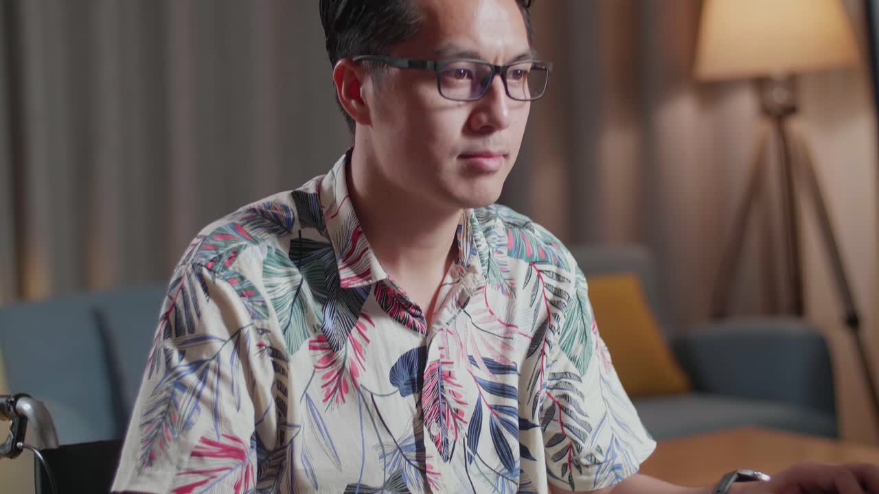 체어에 앉은 아시아인 남자가 집에서 비디오를 편집하는 카메라 에 있는 데스크을 사용하고 있습니다.