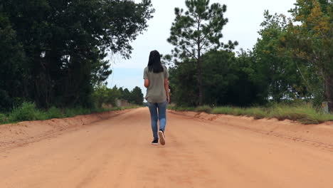 young woman walking alone on a dirt road